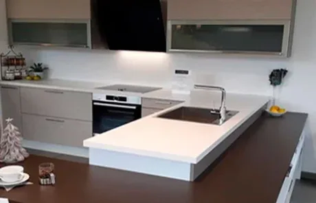 Cocina con bancada oscura, armarios blancos y una isla central.