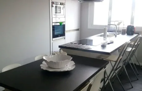 Cocina moderna con bancada negra, armarios claros y una isla espaciosa.