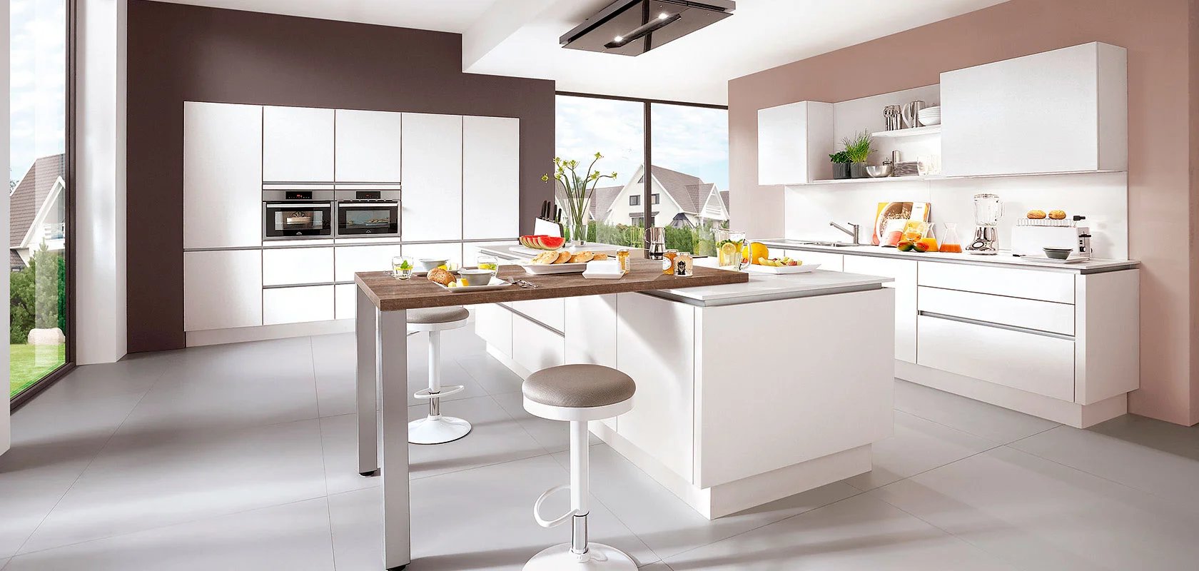 Gran cocina moderna con armarios espaciosos y paredes en tonos marrones y beige, destacando una isla central que combina funciones de encimera y mesa, acompañada de dos sillas.